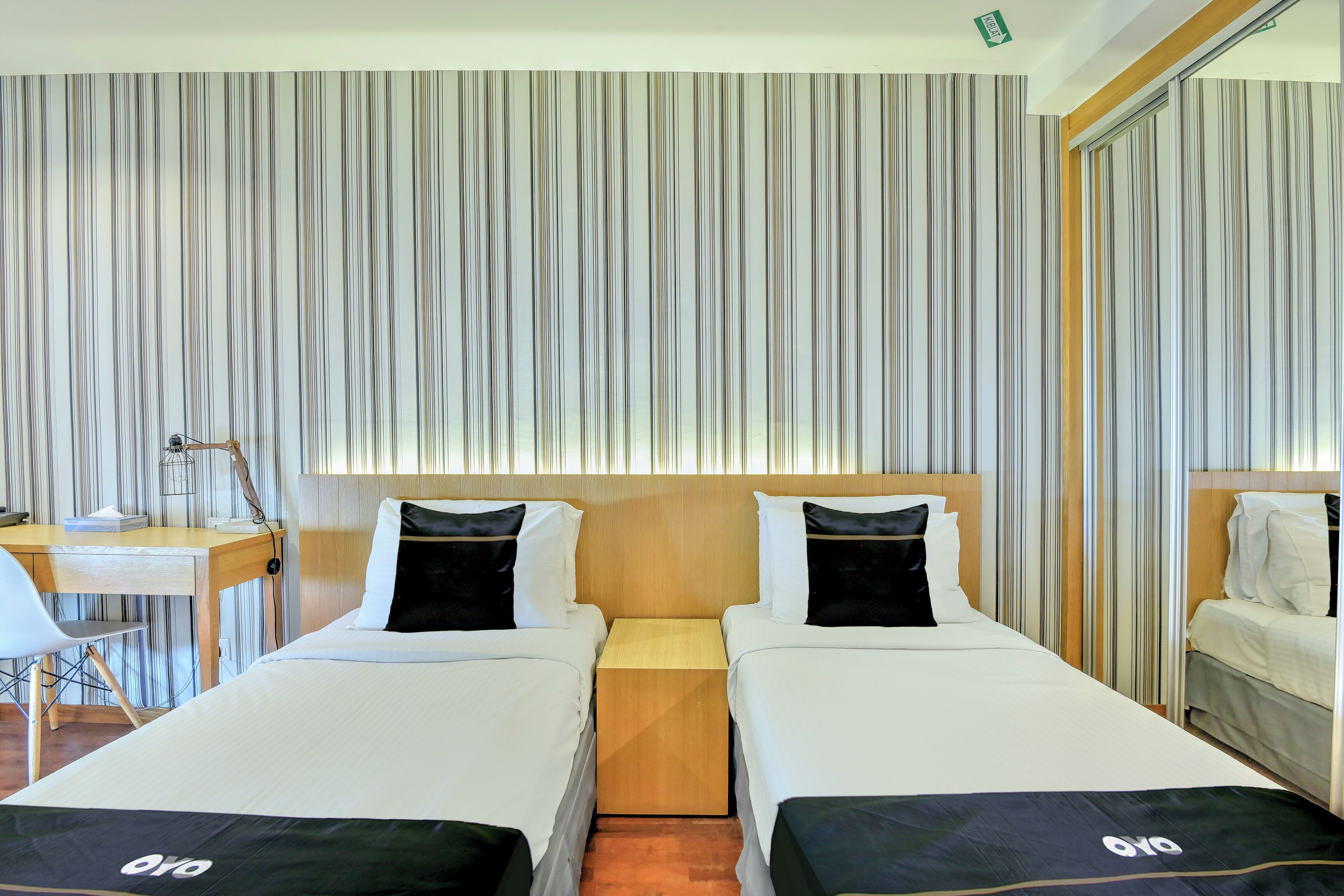 A hotel room with two beds, a desk, and a chair.