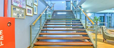 A modern interior with a wooden staircase, glass railings, and a sign with text.