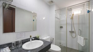 A modern bathroom with a granite countertop, white sink, and a glass-enclosed shower. - Platinum Beach Hotel (Da Nang)