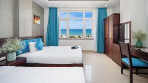 A hotel room with two beds, a view of the ocean, a desk with a chair, and a cabinet. - Platinum Beach Hotel (Da Nang)