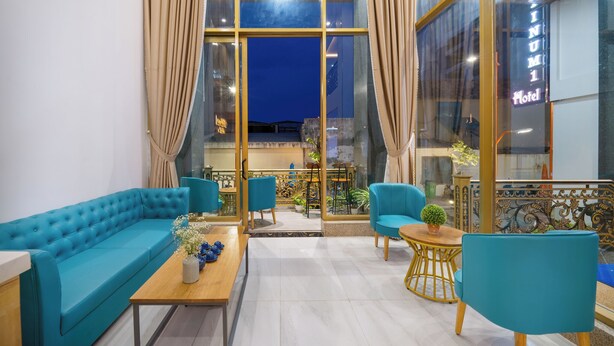 A modern lounge area with a blue sofa, matching chairs, and a wooden coffee table. - Platinum Beach Hotel (Da Nang)