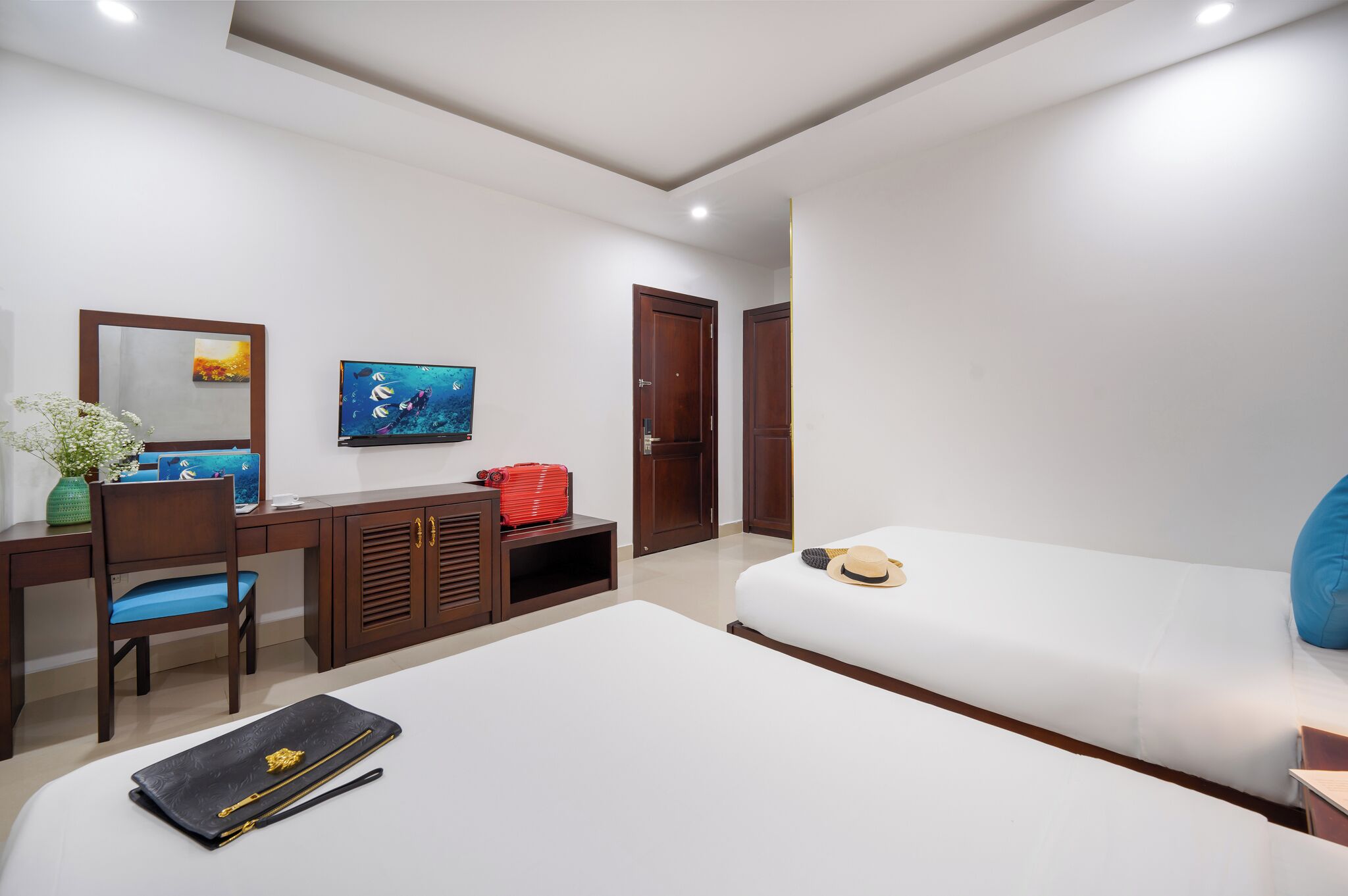 A modern hotel room with a bed, desk, chair, and a TV on the wall.