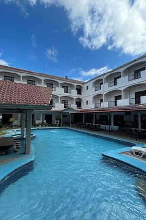 A swimming pool with a white building in the background. - Angeles Palace Hotel (Angeles City)