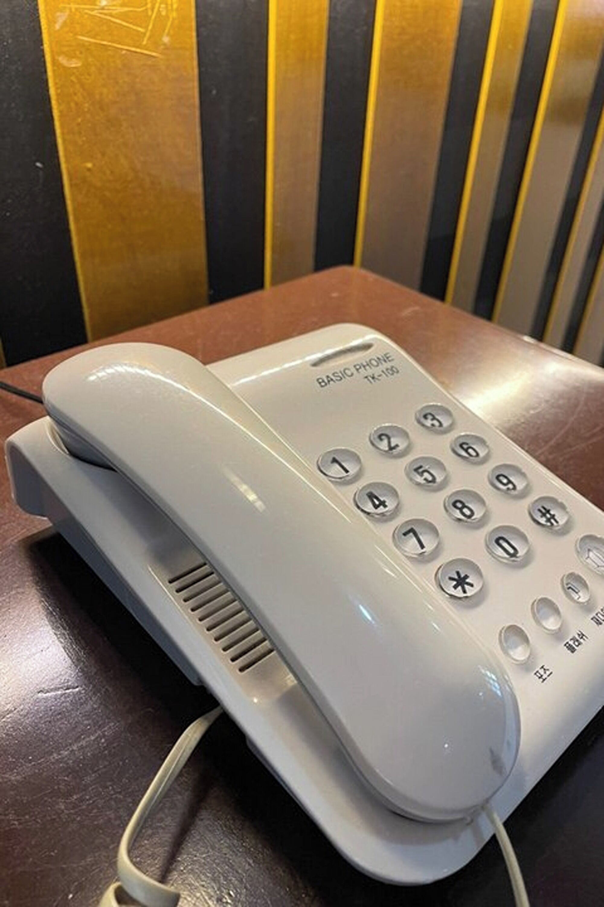 A basic phone with a keypad and a handset resting on a table.