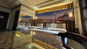Een moderne hotelkamer met een groot bed, een glazen bijzettafeltje en een muurschildering van een stadsgezicht met een reuzenrad.