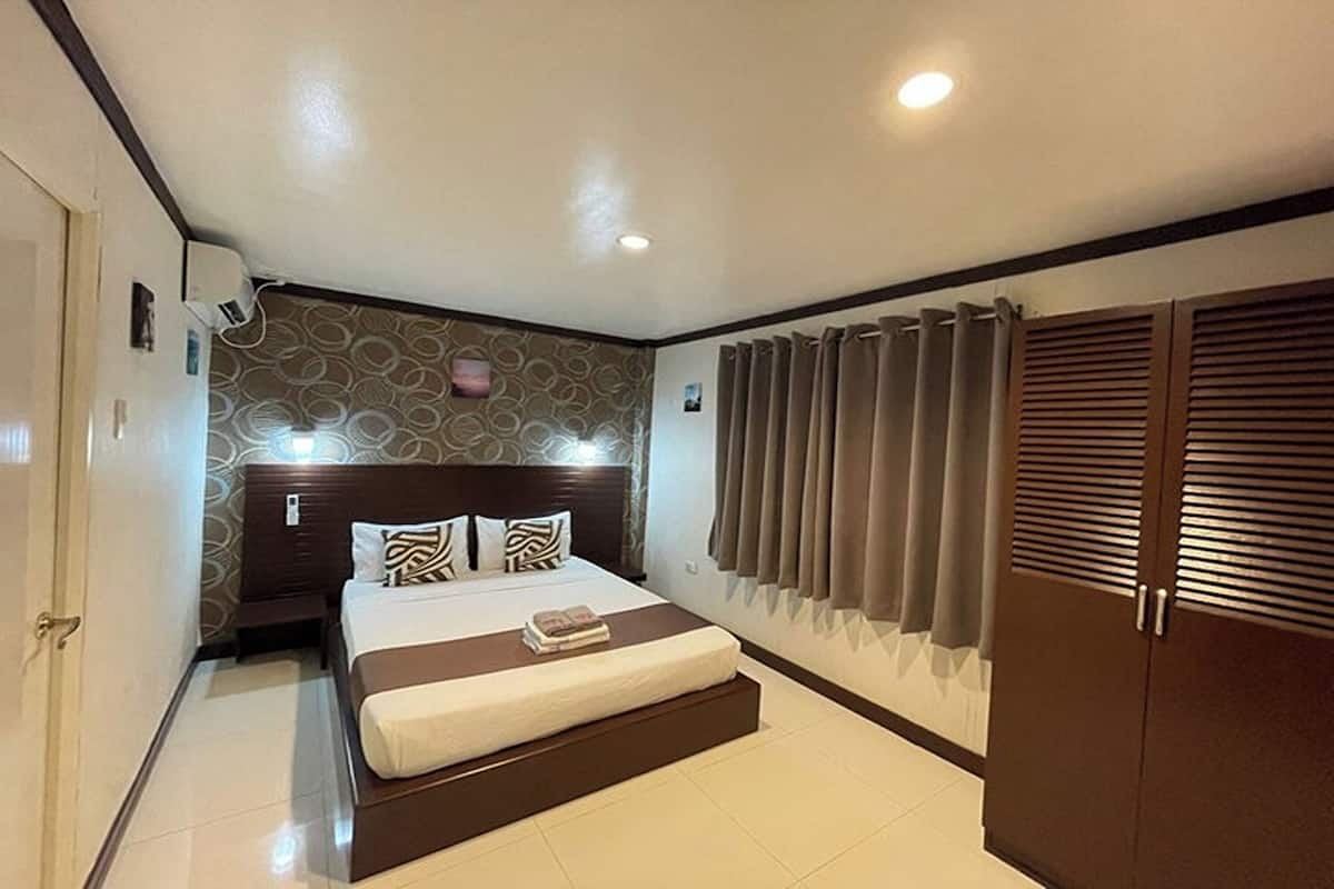 A hotel room with a large bed, a wardrobe, and a ceiling light.