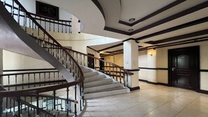 Een meerlaags interieur met een gebogen trap, betegelde vloer en een deur met donker frame.