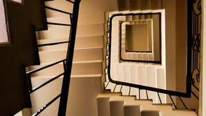 Una escalera de caracol con rellano central y barandilla decorativa.