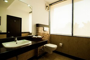 A bathroom with a sink, toilet, and a window.