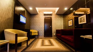 Un vestíbulo moderno con un tapete central, un sofá rojo, un sillón amarillo y un televisor en la pared.