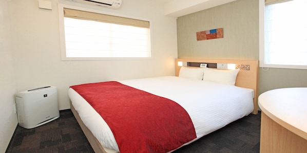 A hotel room with a bed, a bedside table, a window with blinds, an air conditioning unit, and a wall-mounted artwork. - Urban Hotel Kyoto Nijo Premium (Kyoto)