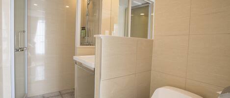 Un baño moderno con cabina de ducha de vidrio, un lavabo blanco y un inodoro.