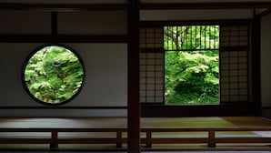 A traditional Japanese room with tatami flooring, a circular window with a forest view, and sliding doors with a grid pattern. - Urban Hotel Kyoto Nijo Premium (Kyoto)