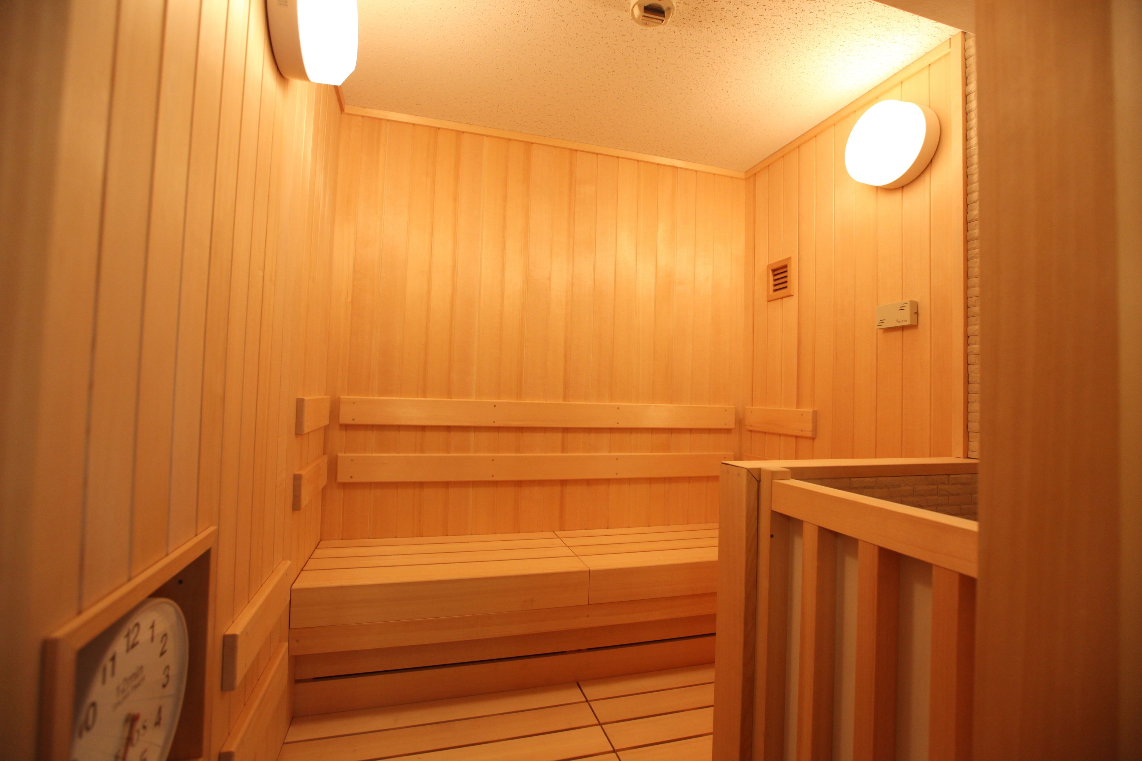 A wooden sauna with benches and a clock on the wall.