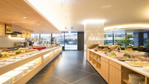 A modern buffet setup with multiple food stations, wooden cabinetry, and a spacious layout. - Urban Hotel Kyoto Nijo Premium (Kyoto)