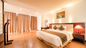 Habitación de hotel con una cama grande, un escritorio, una silla, una mesita de noche y un cuadro en la pared.