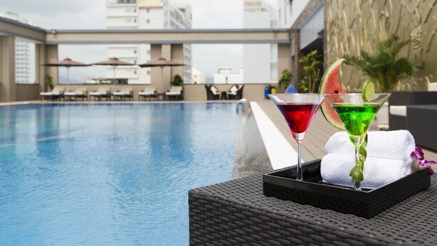 Zona junto a la piscina con una mesa de bar, dos cócteles y una toalla.