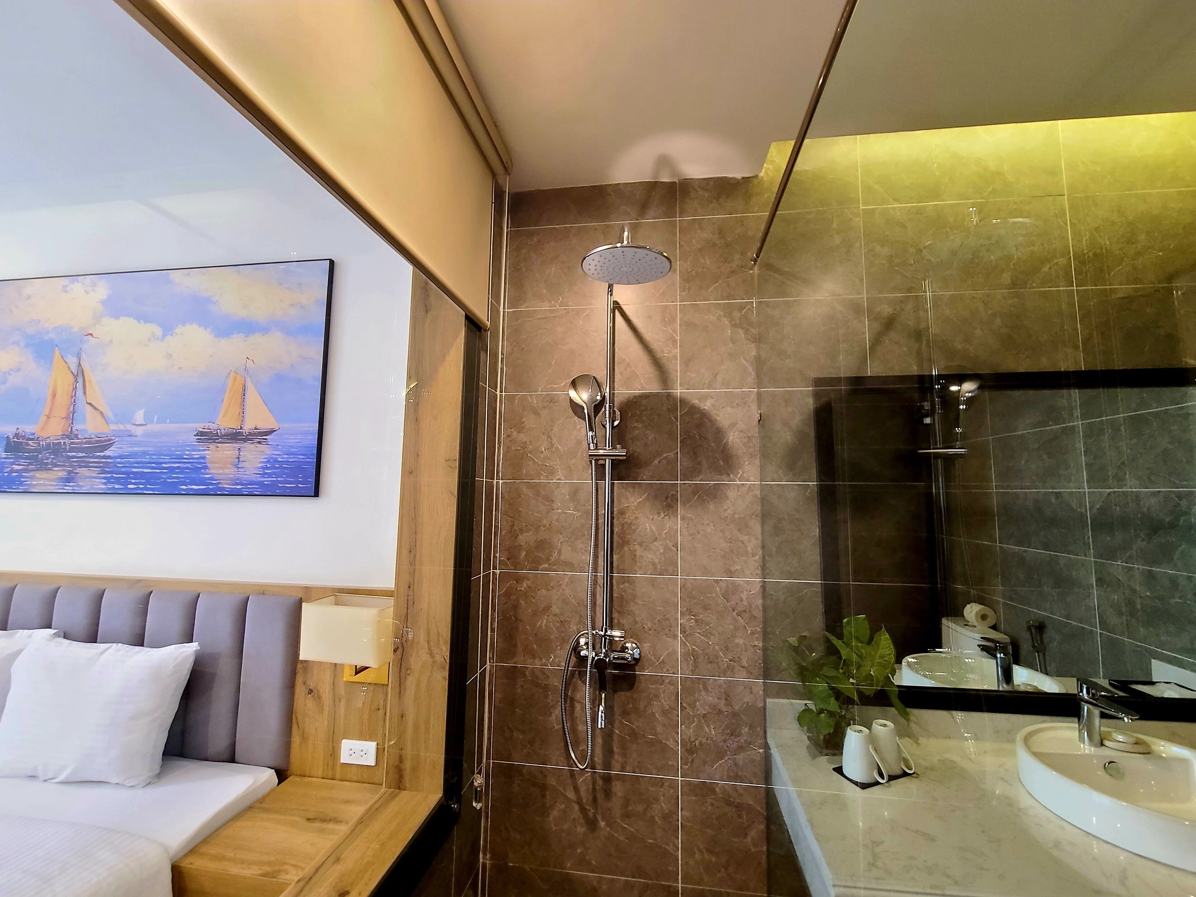 A modern bathroom with a shower, a sink, and a painting of sailboats on the wall.