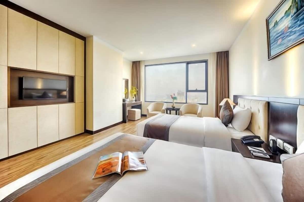 A hotel room with two beds, a TV, a desk, and a large window.