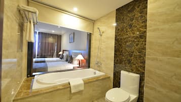 A modern bathroom with a large mirror, a bathtub, and a toilet.