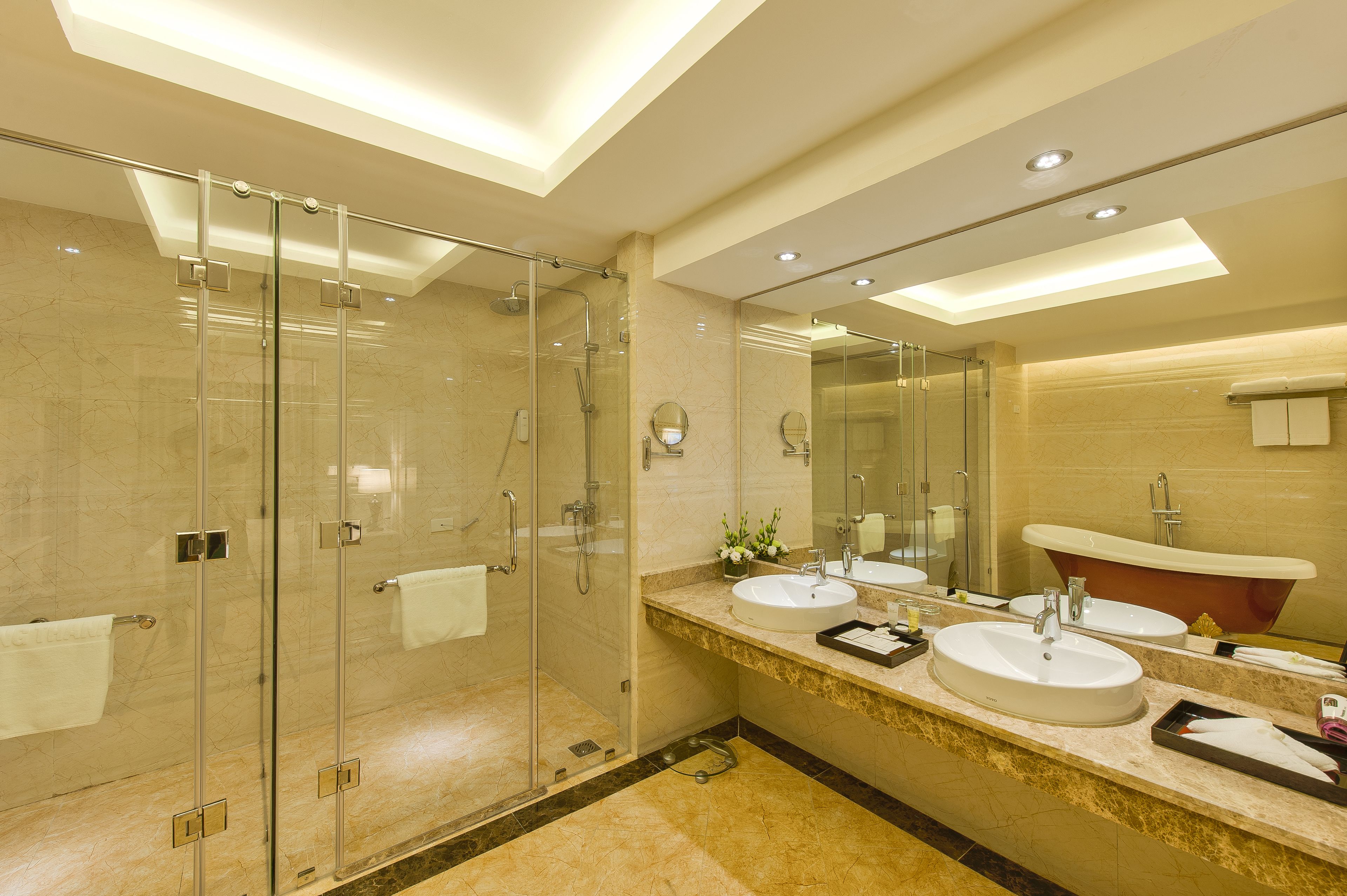 A modern bathroom with a glass-enclosed shower, two sinks, and a large mirror.