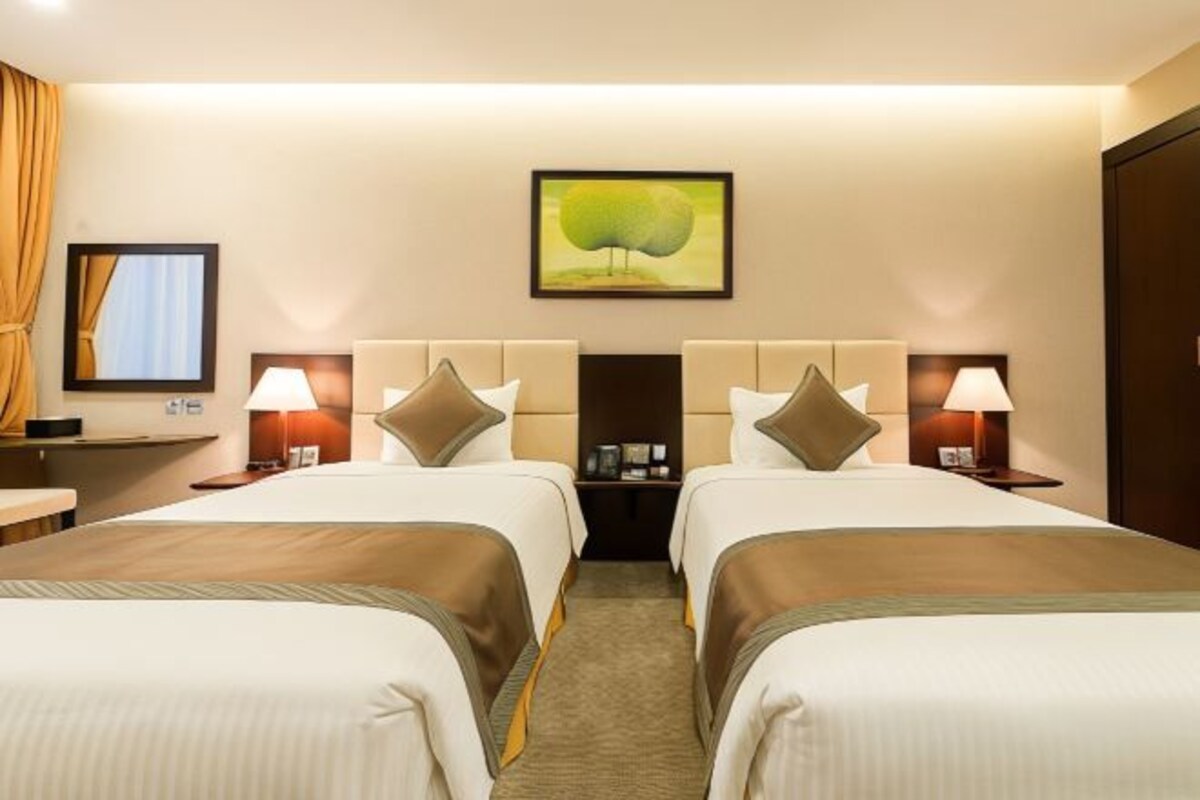 Una habitación de hotel con dos camas, un escritorio y una mesita de noche con lámparas.