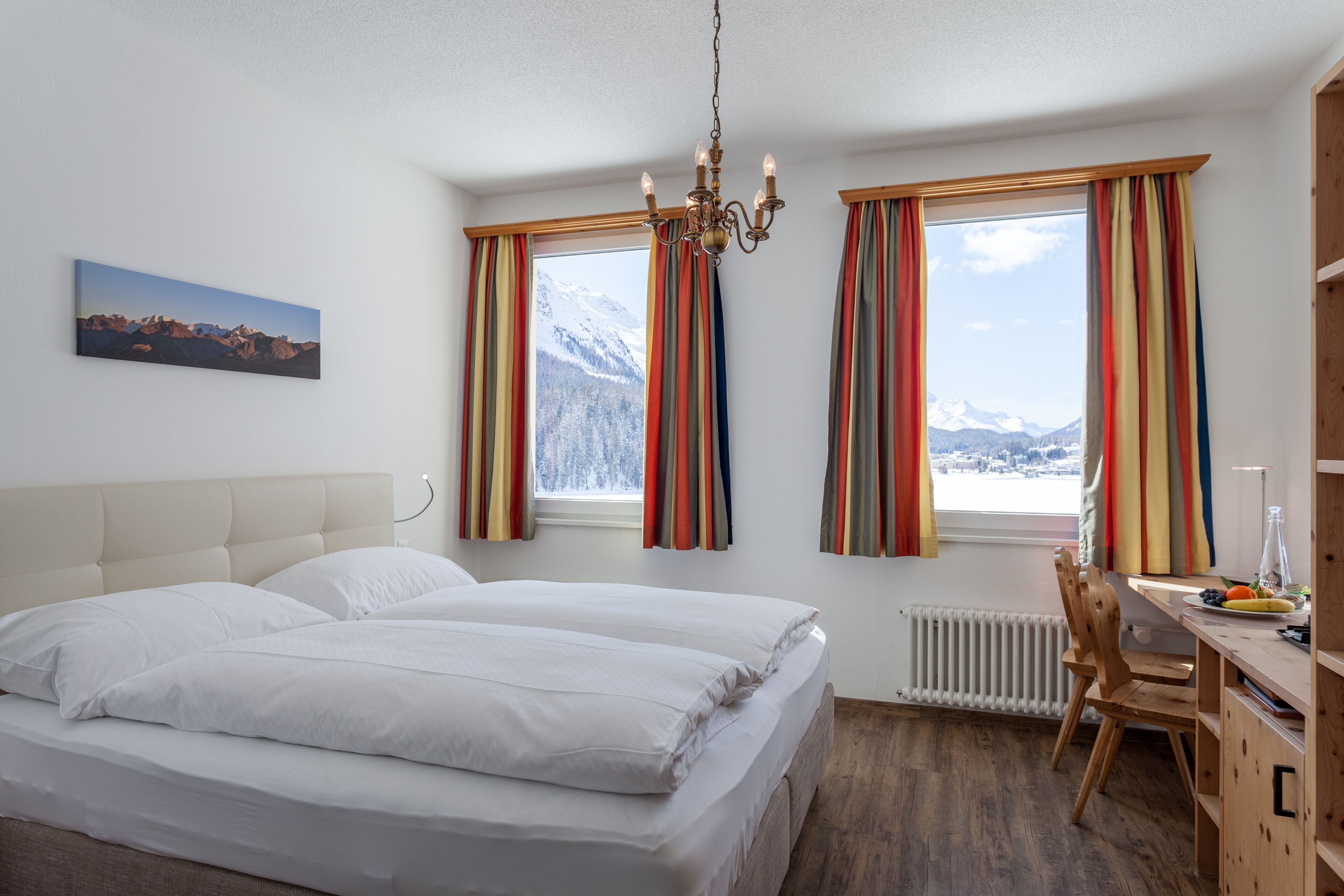 A hotel room with a bed, a desk, and a view of mountains.