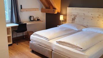 Une chambre à coucher avec un grand lit, un bureau avec une chaise, un radiateur et une fenêtre avec des rideaux.