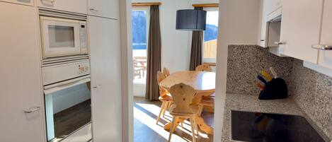A modern kitchen with white cabinets, a granite countertop, and a dining area with wooden furniture.