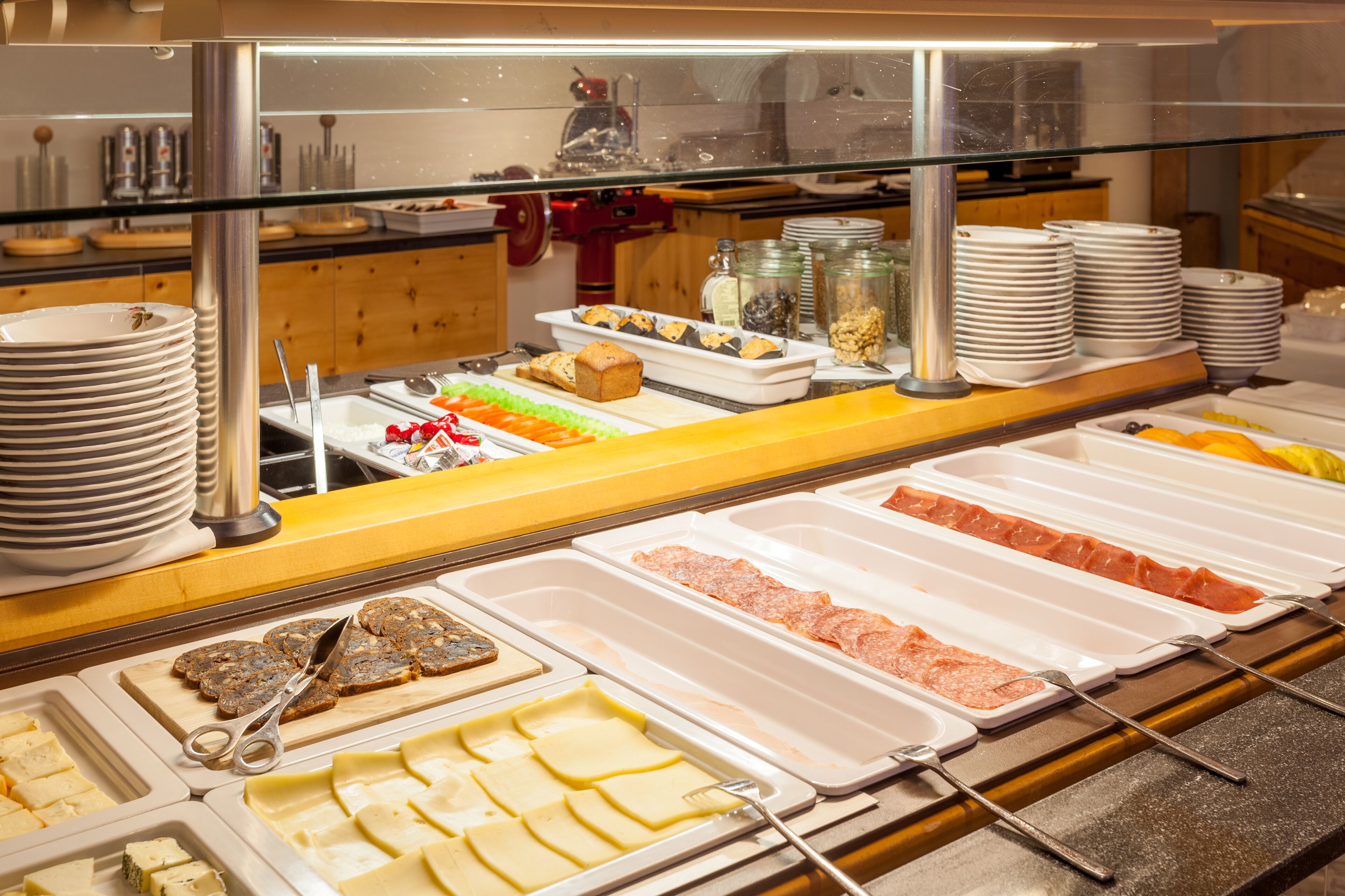 Un buffet proposant une variété de plats, notamment des viandes, des fromages et des pâtisseries.