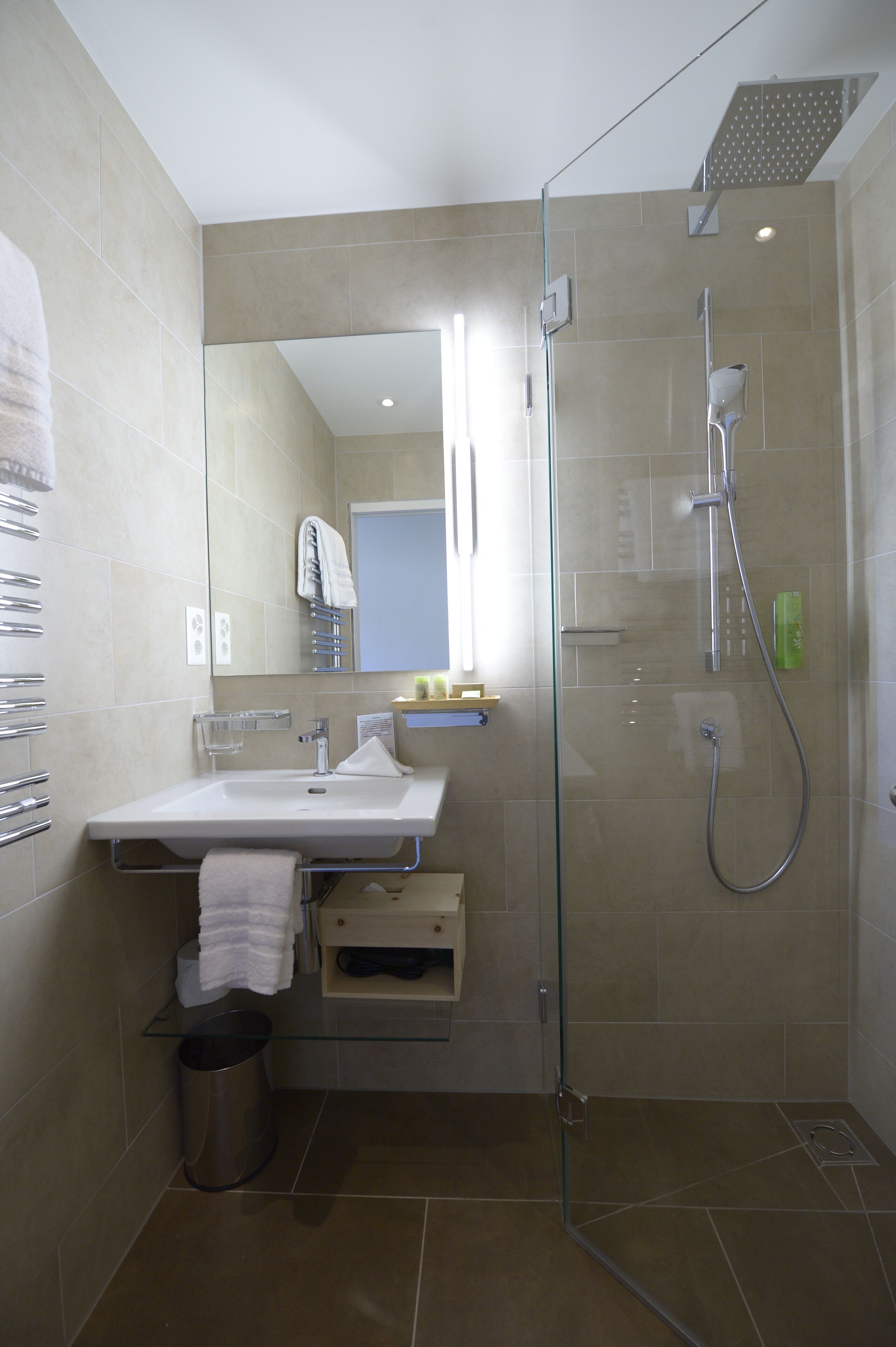 A modern bathroom with a glass-enclosed shower, a sink with a towel rack, and a mirror.