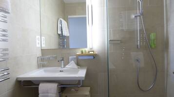 A modern bathroom with a glass-enclosed shower, a sink with a towel rack, and a mirror.
