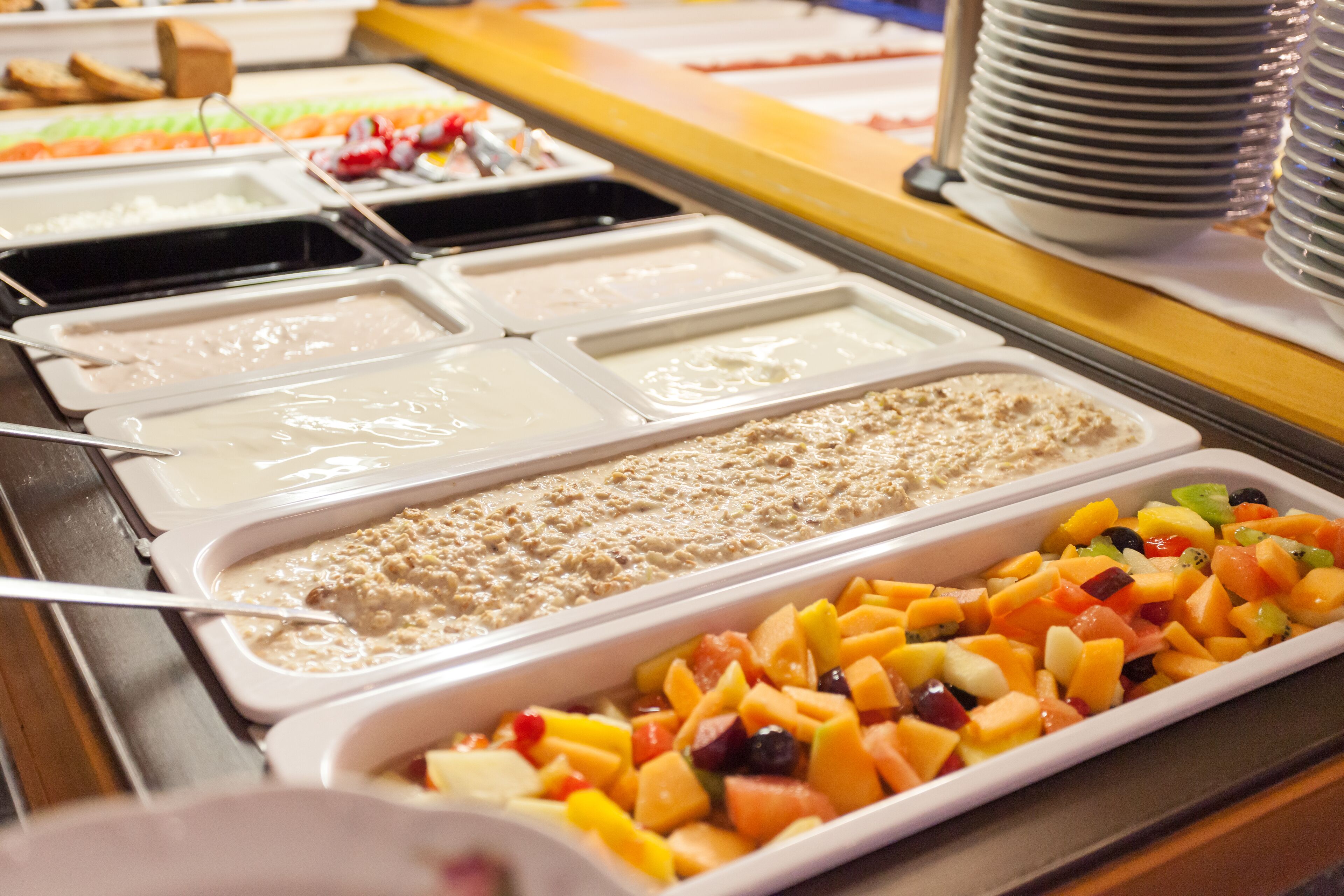 A buffet with various food options including fruits, yogurt, and cereal.