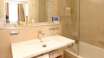 Une salle de bain moderne avec une douche à parois de verre, un grand miroir et un lavabo blanc.