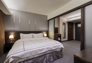 Een hotelkamer met een groot bed, nachtlampjes, een garderobe, een spiegel en een bureau.