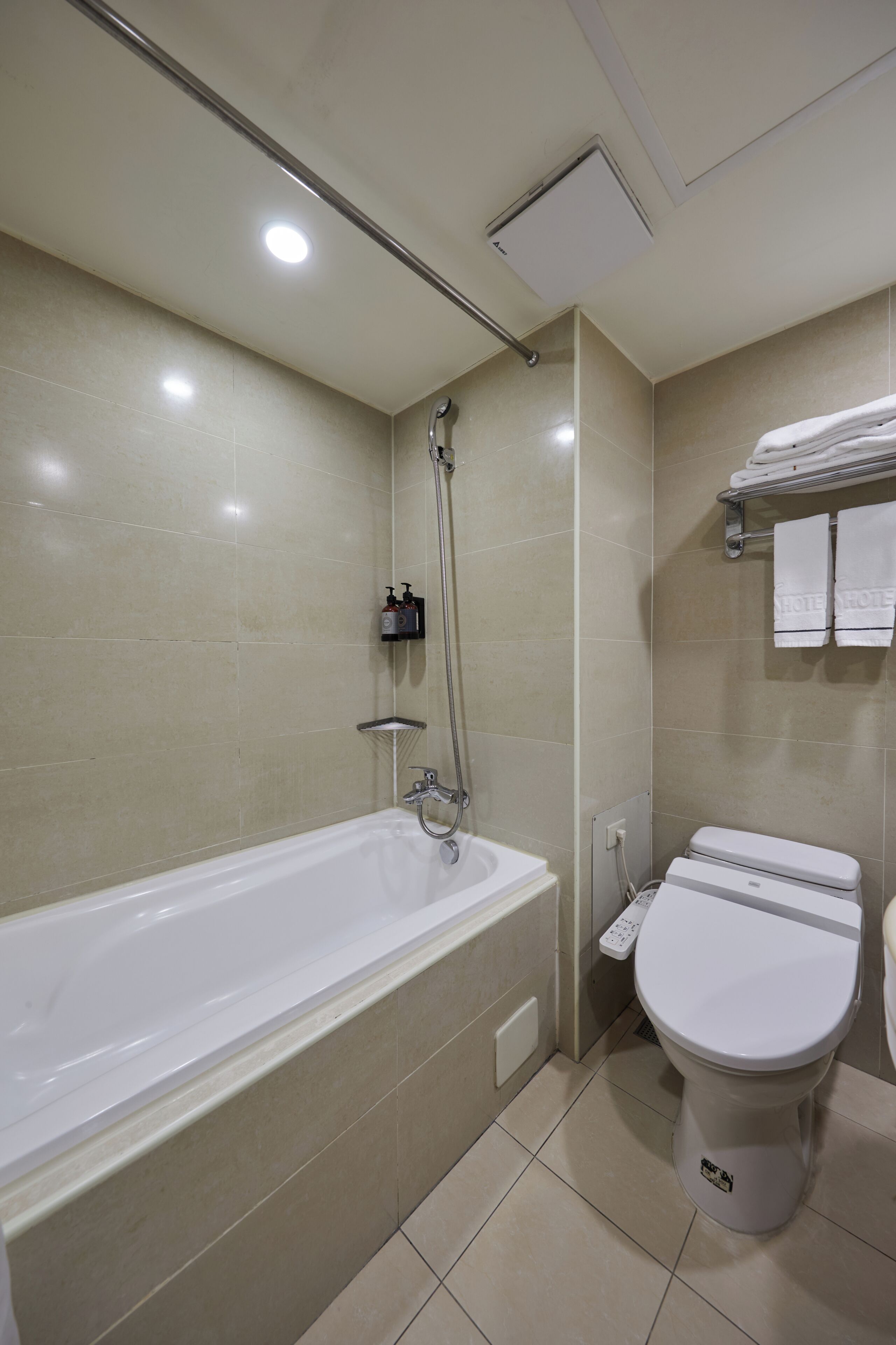 A bathroom with a bathtub, toilet, and a shelf with toiletries.