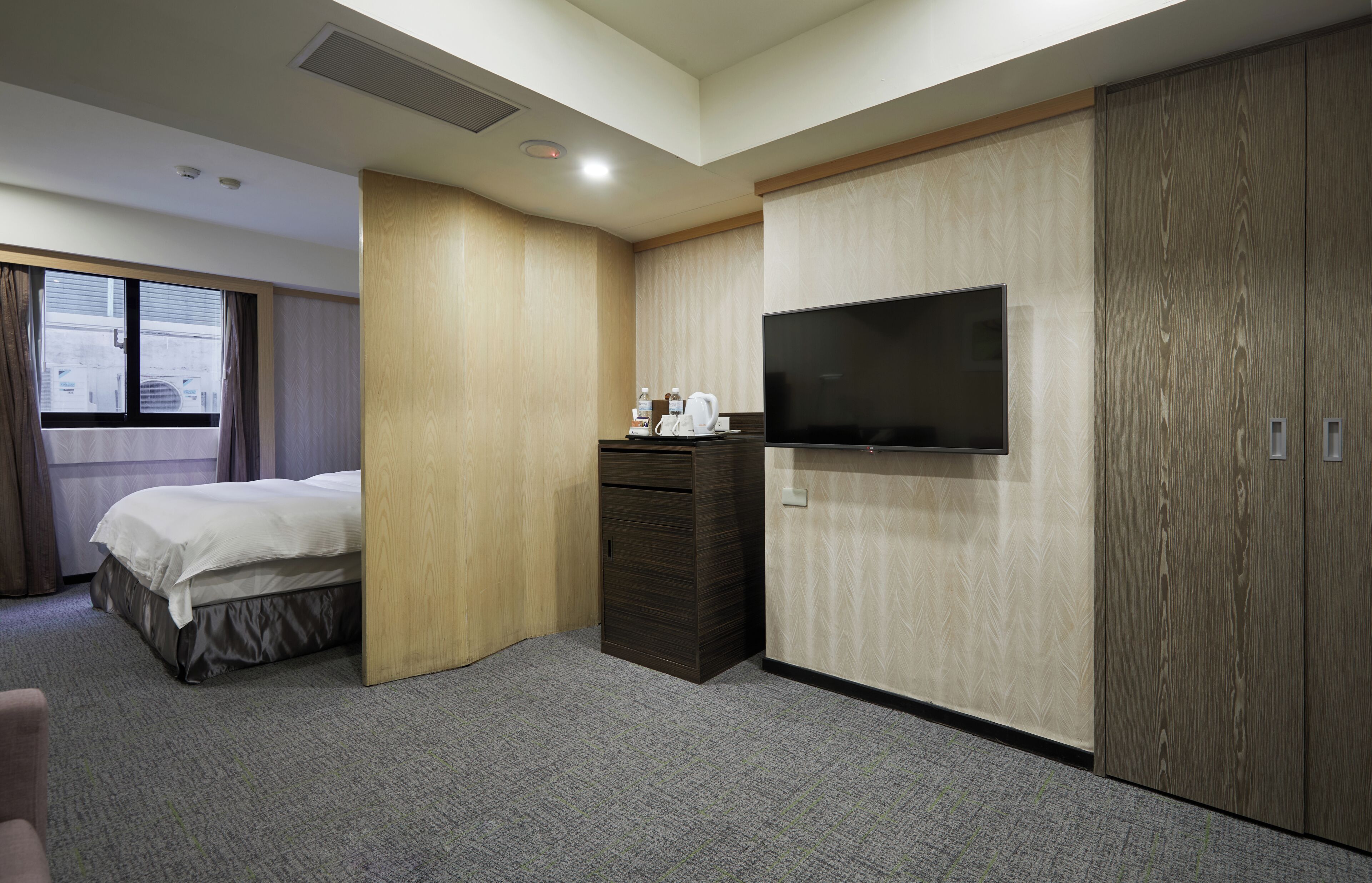 A hotel room with a bed, a TV, a dresser, and a wardrobe.