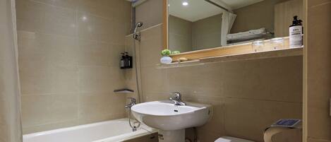 Un baño con bañera, lavamanos, inodoro y espejo.