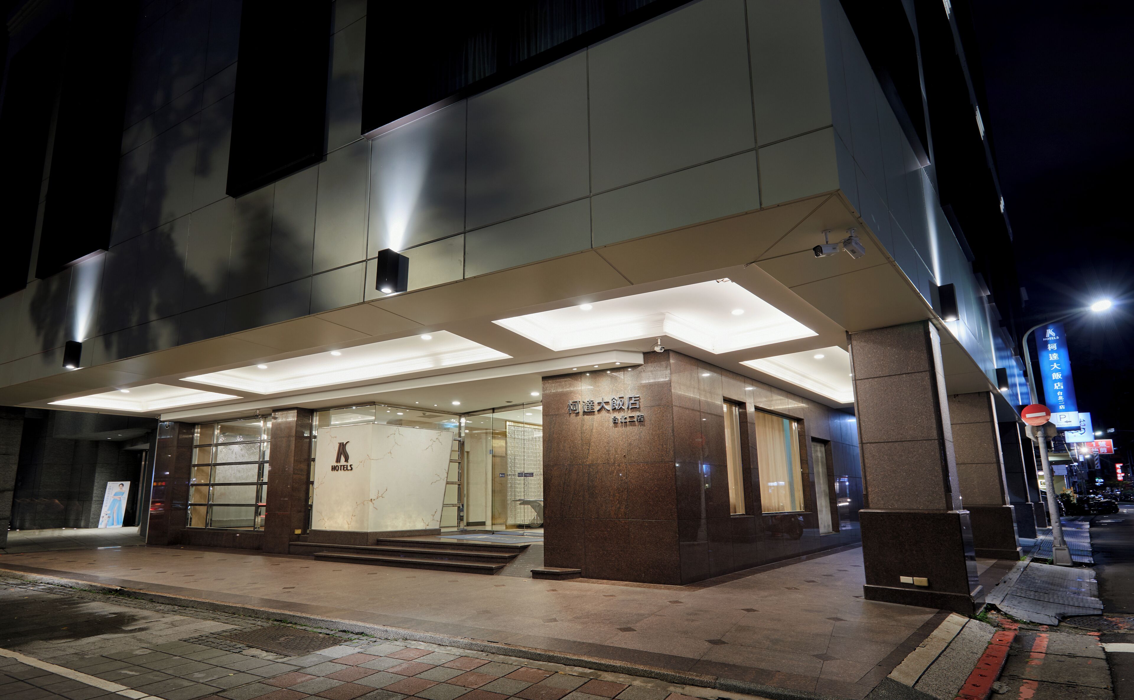 A hotel entrance with a modern design, featuring a prominent entrance, a visible signboard, and a well-lit facade.
