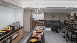 A modern kitchen with a long counter displaying various food items and a dining area with chairs and tables. - K Hotel - Taipei II (Taipei)