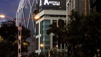 A modern hotel with a prominent 'HOTELS' sign, surrounded by urban traffic and buildings.