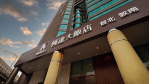 Un hotel con fachada moderna, amplias columnas y señalización que indica que es un hotel.