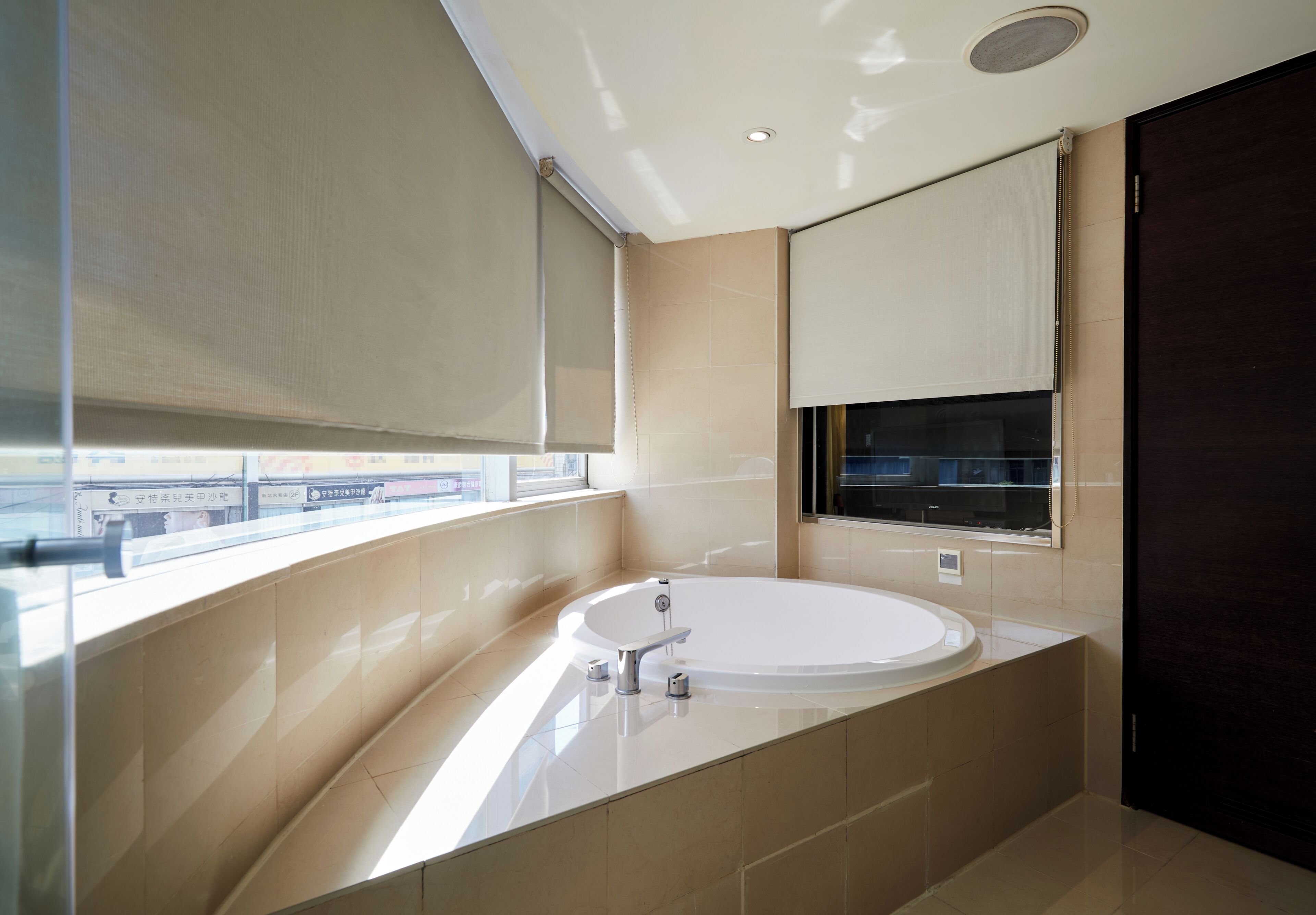 Un baño moderno con una bañera grande, una ventana con vistas y una puerta oscura.