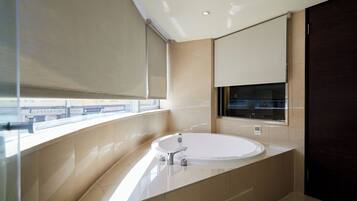 Un baño moderno con una bañera grande, una ventana con vistas y una puerta oscura.
