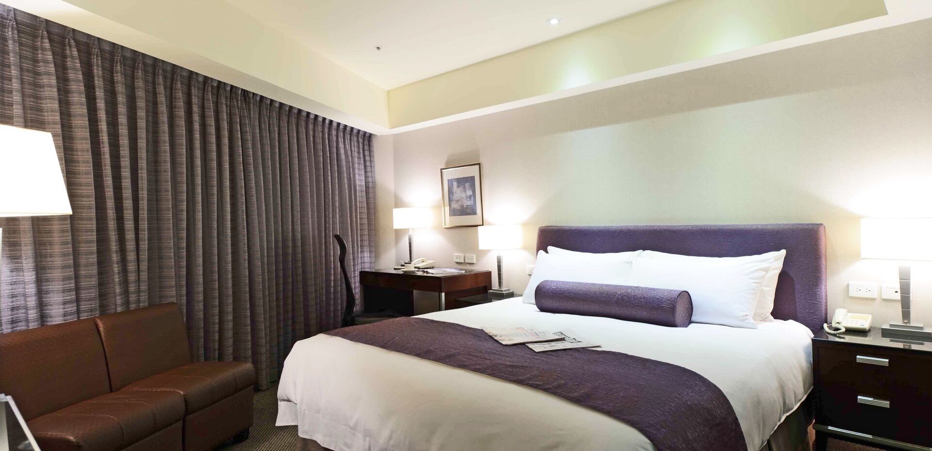 Habitación de hotel con una cama grande, un escritorio, una silla y una mesita de noche.