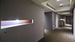 Een moderne hal met een houten vloer, inbouwverlichting en een ventilatiesysteem aan het plafond.