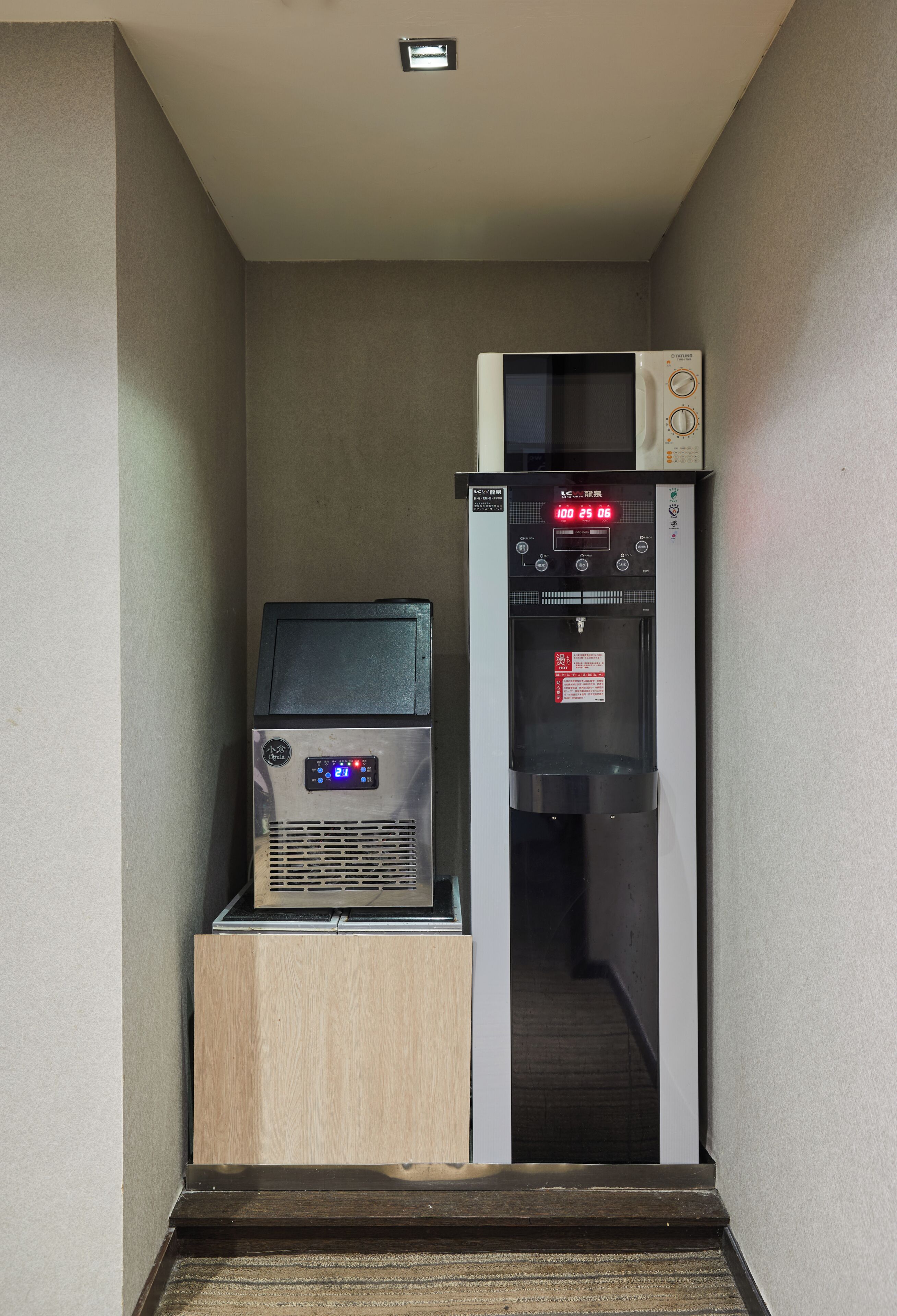 A narrow hallway with a vending machine and a microwave on a counter.