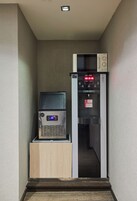 A narrow hallway with a vending machine and a microwave on a counter.