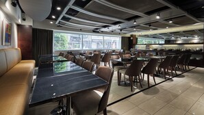 Een modern restaurant met een lange gemeenschappelijke tafel, individuele zitjes en uitzicht op de stad.