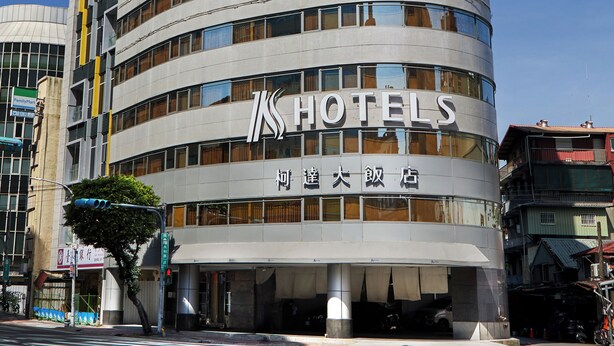 Een modern hotel met een gebogen gevel, meerdere verdiepingen en een opvallend bord.